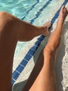 Young womanÃ¢â¬â¢s long tan legs in bright blue pool water